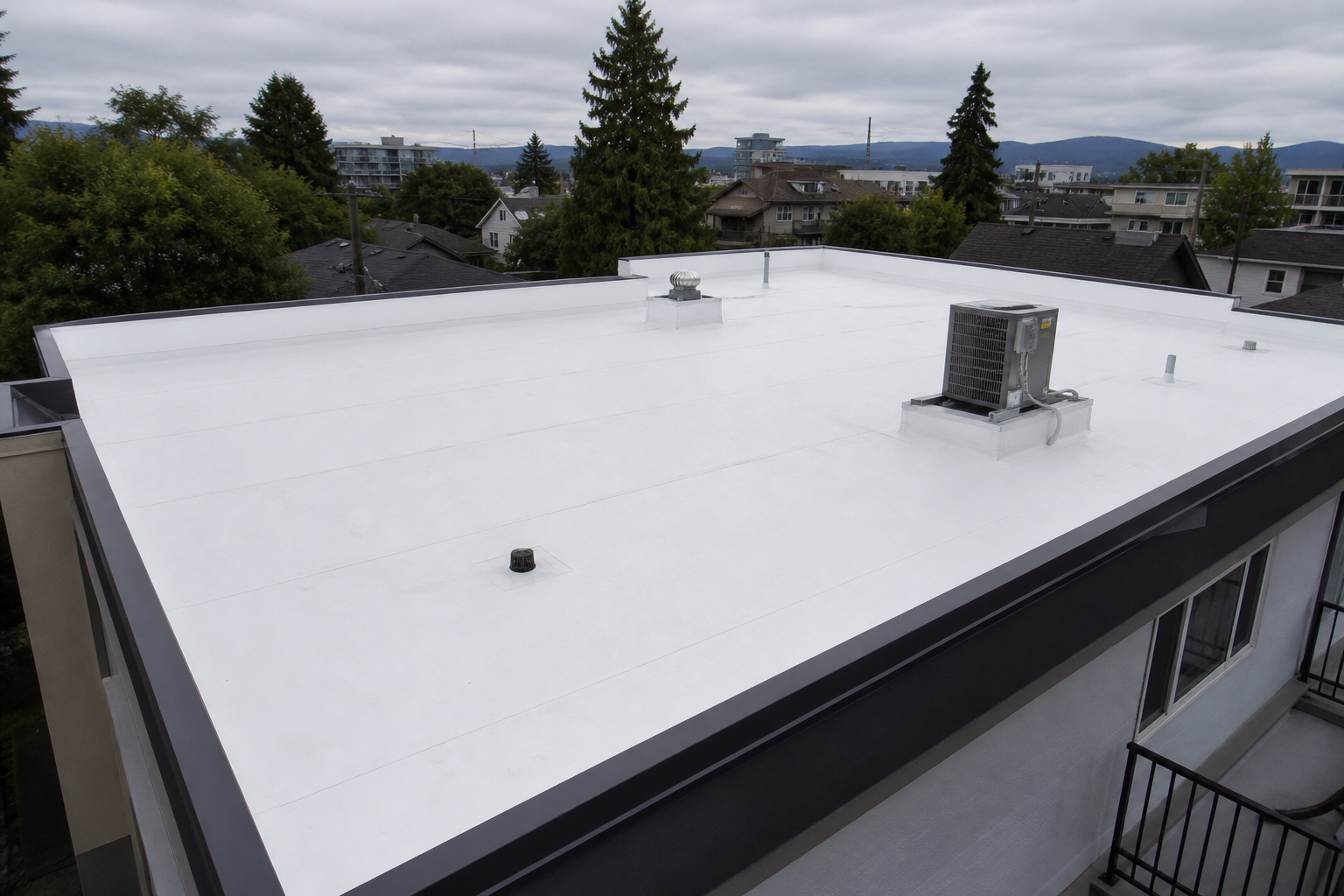 Completed white TPO membrane roof with clean welded seams, drains, and flashed equipment curb