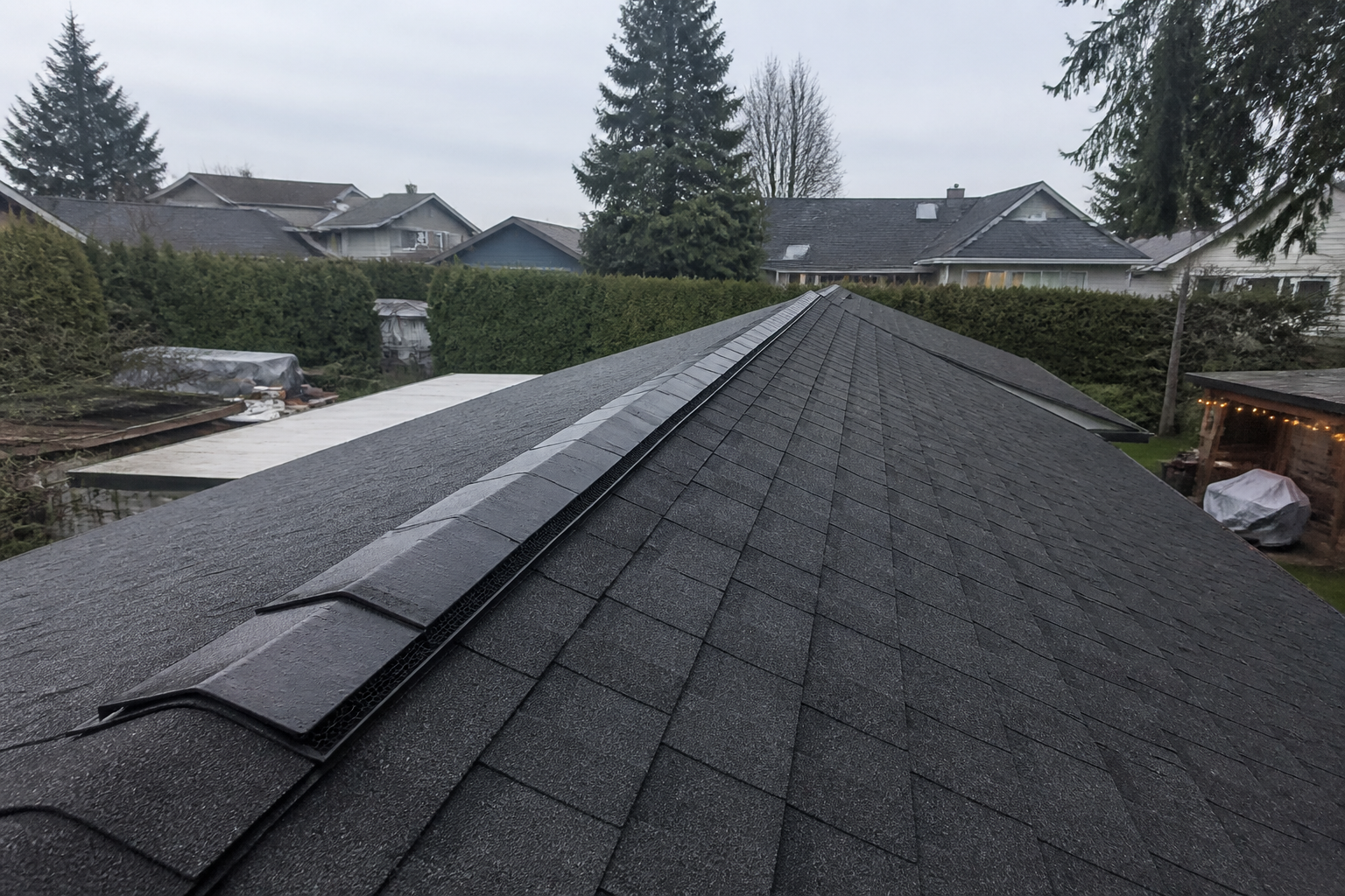 Continuous ridge vent installed along the peak of a dark charcoal asphalt shingle roof